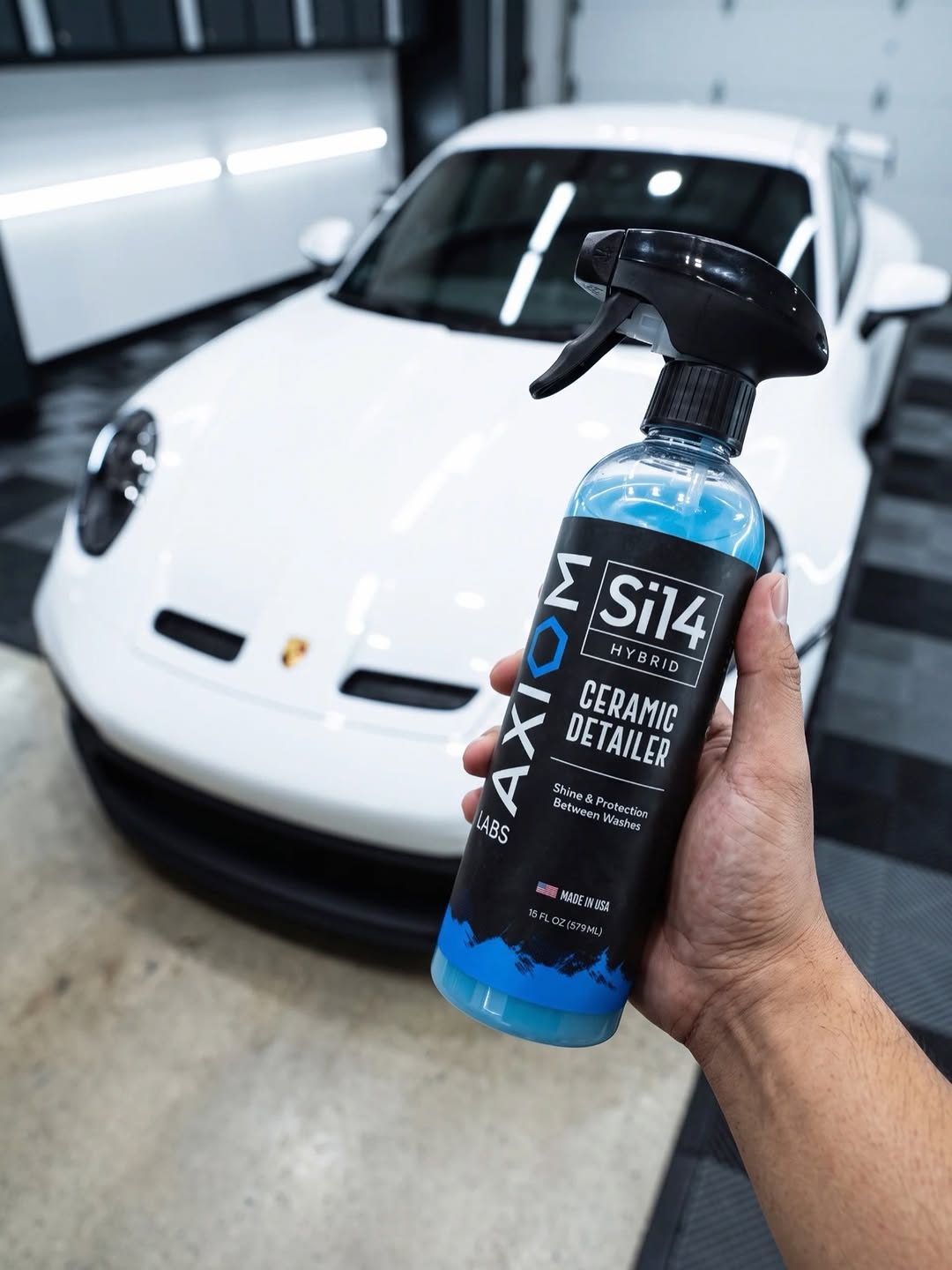 Si14 Hybrid Ceramic Detailer held in front of a white Porsche